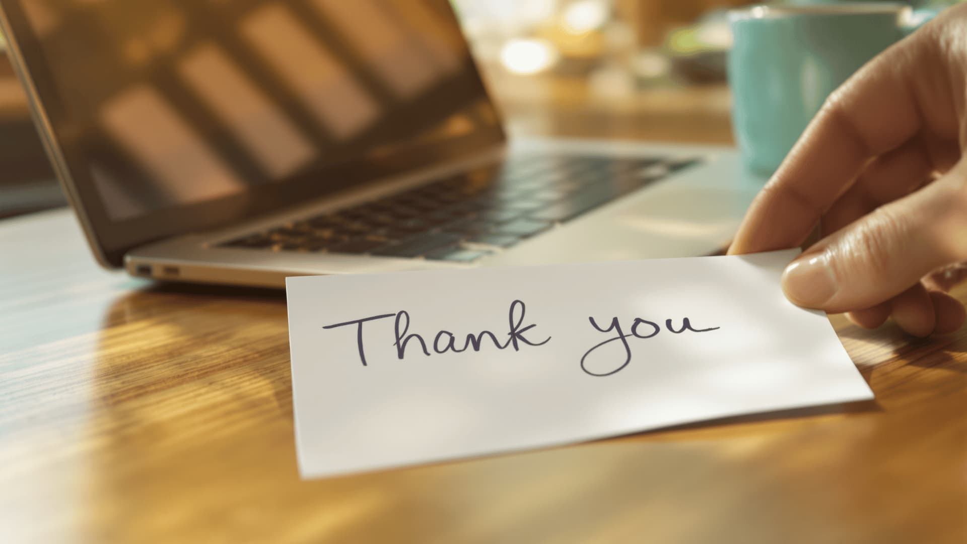 Handwritten thank-you note beside a laptop symbolizing personal lead nurturing