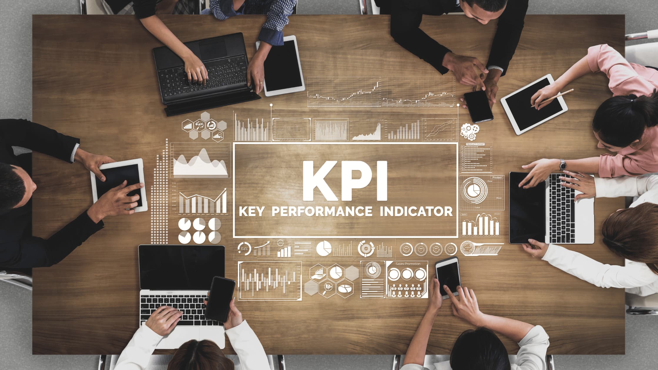 Team analyzing KPI data with laptops and tablets in a strategy meeting